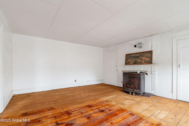 2127 2nd Ave, Watervliet, NY 12189 - unfurnished living room featuring light wood-type flooring, a wood stove, a drop ceiling, and baseboards