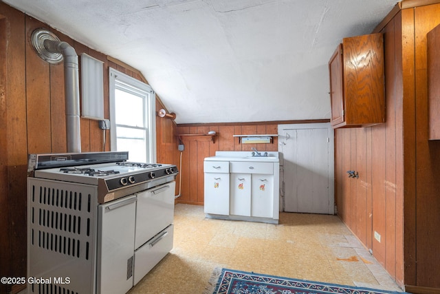 2127 2nd Ave, Watervliet, NY 12189 - kitchen featuring white range with gas stovetop, light flooring, wooden walls, vaulted ceiling, and brown cabinetry