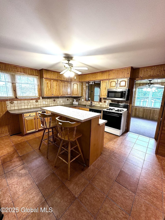 2618 Stanton St, Rotterdam, NY 12306 - kitchen with range with gas stovetop, stainless steel microwave, a sink, backsplash, and a kitchen island