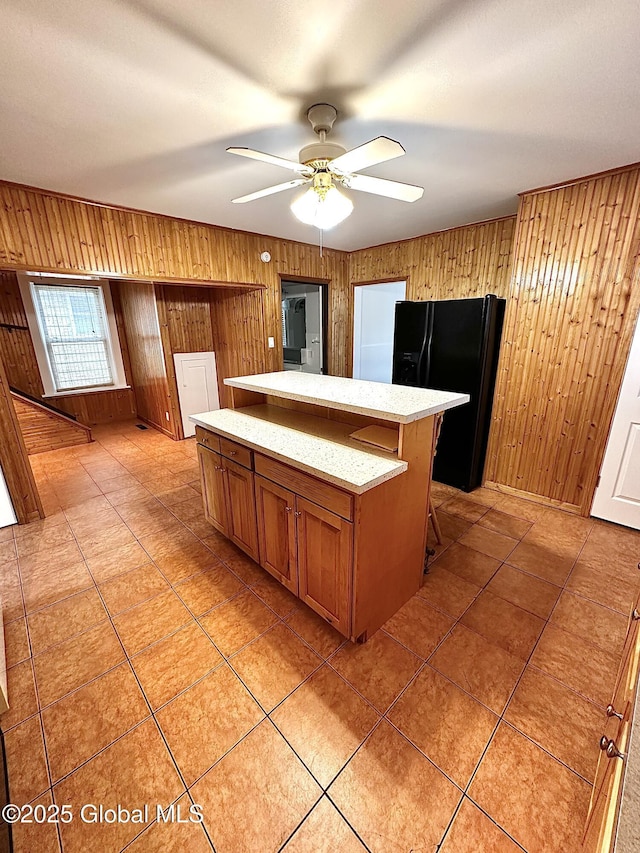 2618 Stanton St, Rotterdam, NY 12306 - kitchen with black fridge with ice dispenser, wood walls, brown cabinets, a center island, and a ceiling fan