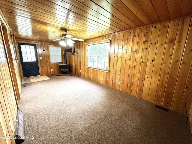 2618 Stanton St, Rotterdam, NY 12306 - unfurnished living room featuring a wood stove, wood ceiling, carpet flooring, and wooden walls