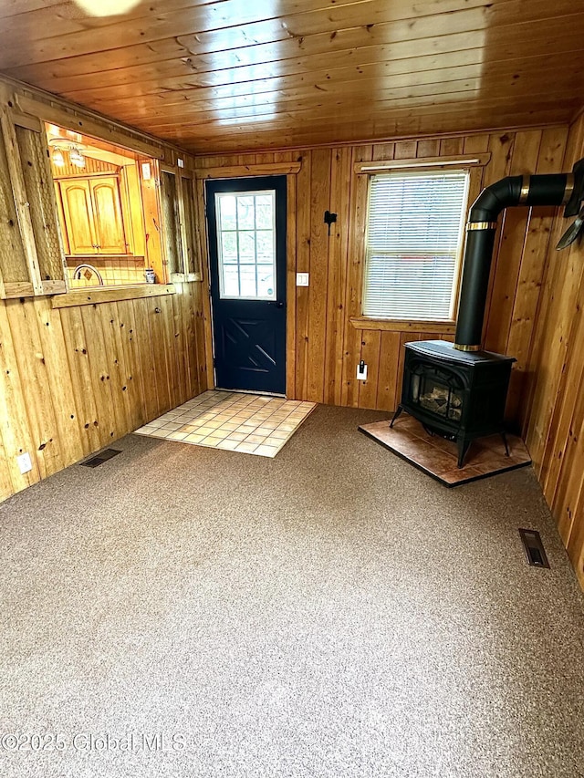 2618 Stanton St, Rotterdam, NY 12306 - carpeted entryway featuring wood walls, wooden ceiling, and a wood stove