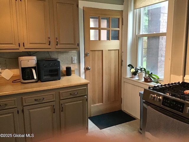 281 10th St, Troy, NY 12180 - kitchen featuring gas stove, tasteful backsplash, light countertops, and light tile patterned floors