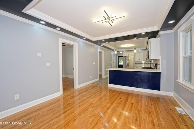 35 Wallace St, Scotia, NY 12302 - kitchen with freestanding refrigerator, ornamental molding, a tray ceiling, light countertops, and a peninsula