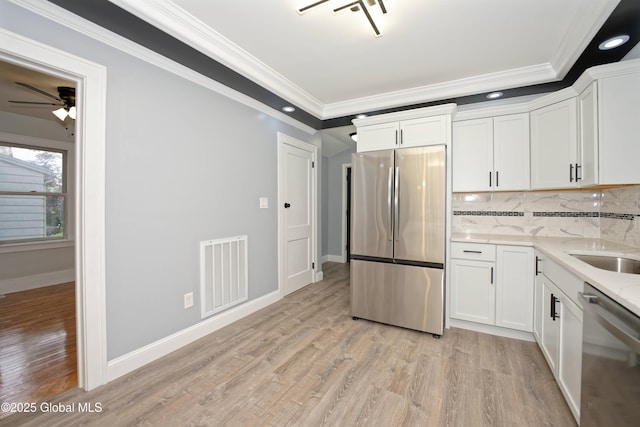 35 Wallace St, Scotia, NY 12302 - kitchen featuring stainless steel appliances, ornamental molding, tasteful backsplash, light wood-type flooring, and white cabinets