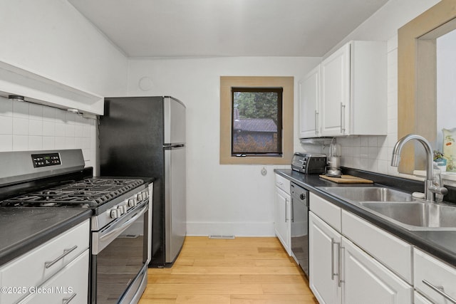 406 Northern Pines Rd, Wilton, NY 12831 - kitchen with stainless steel appliances, a sink, white cabinets, light wood-type flooring, and dark countertops
