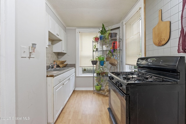 797 Eastern Ave, Schenectady, NY 12308 - kitchen featuring black gas range, a sink, white cabinetry, light wood-style flooring, and decorative backsplash