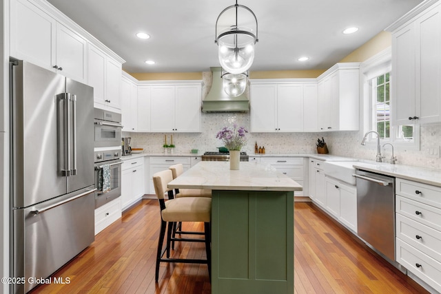41 Tipperary Way, Clifton Park, NY 12019 - kitchen with appliances with stainless steel finishes, custom exhaust hood, light wood-style floors, white cabinetry, and recessed lighting