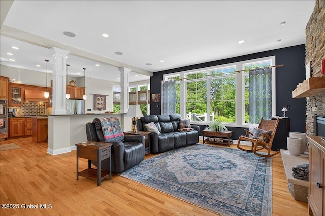19 Hidden Farm Ln, Halfmoon, NY 12118 - living room featuring decorative columns, light wood finished floors, a stone fireplace, and recessed lighting