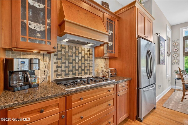 19 Hidden Farm Ln, Halfmoon, NY 12118 - kitchen with appliances with stainless steel finishes, custom range hood, light wood-style floors, glass insert cabinets, and brown cabinets