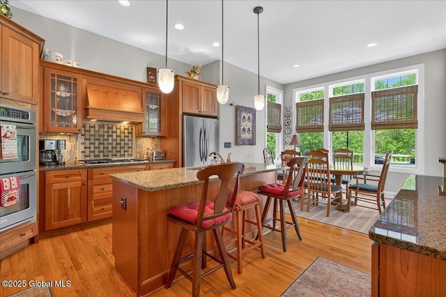 19 Hidden Farm Ln, Halfmoon, NY 12118 - kitchen with appliances with stainless steel finishes, brown cabinetry, custom exhaust hood, light wood-style floors, and recessed lighting