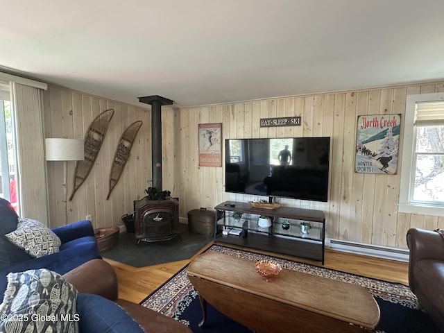 34 Park Rd, Johnsburg, NY 12843 - living room featuring a baseboard heating unit, wood finished floors, wood walls, and a wood stove