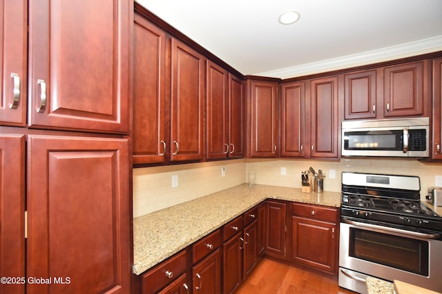 509 Lois Ln, Niskayuna, NY 12304 - kitchen featuring stainless steel appliances, reddish brown cabinets, tasteful backsplash, light stone countertops, and light wood-style flooring