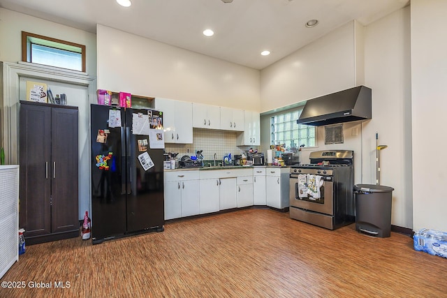 1466 3rd St, Rensselaer, NY 12144 - kitchen featuring freestanding refrigerator, stainless steel gas stove, wall chimney exhaust hood, white cabinets, and dark countertops