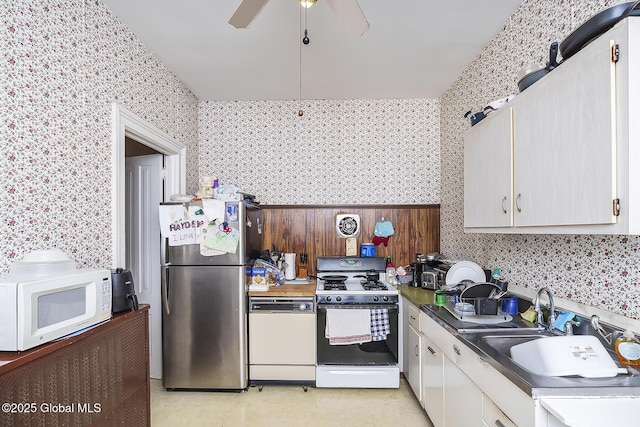 1466 3rd St, Rensselaer, NY 12144 - kitchen with wallpapered walls, white appliances, a ceiling fan, a sink, and white cabinetry