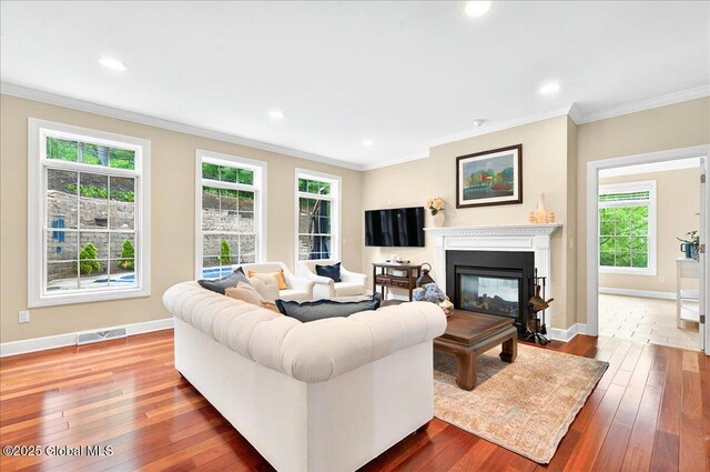 779 Waldens Pond, Guilderland, NY 12203 - living room with dark wood finished floors, baseboards, crown molding, a glass covered fireplace, and recessed lighting