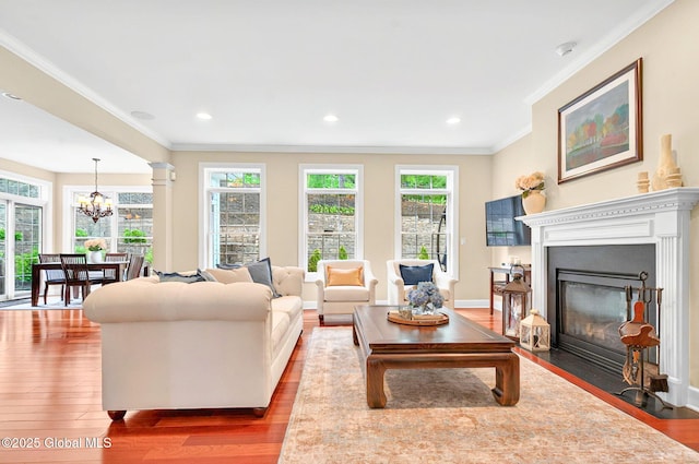 779 Waldens Pond, Guilderland, NY 12203 - living room featuring ornamental molding, wood finished floors, healthy amount of natural light, a chandelier, and a fireplace with flush hearth