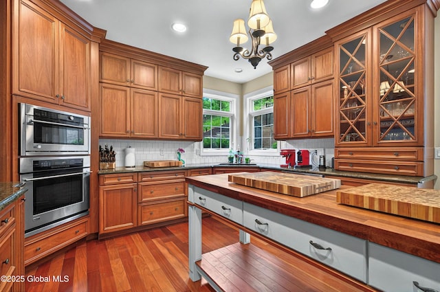 779 Waldens Pond, Guilderland, NY 12203 - kitchen with butcher block countertops, double oven, tasteful backsplash, dark wood-style floors, and brown cabinets