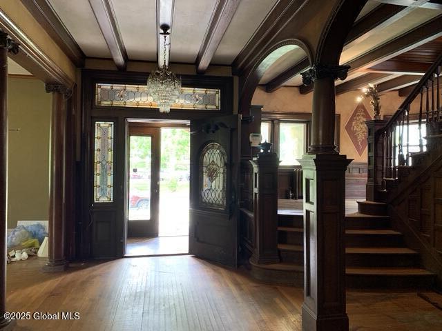 1077 University Pl, Schenectady, NY 12308 - entryway featuring beam ceiling, wood-type flooring, ornate columns, stairs, and a chandelier