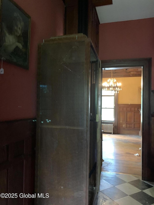 1077 University Pl, Schenectady, NY 12308 - hall with radiator heating unit, a chandelier, a wainscoted wall, and light floors