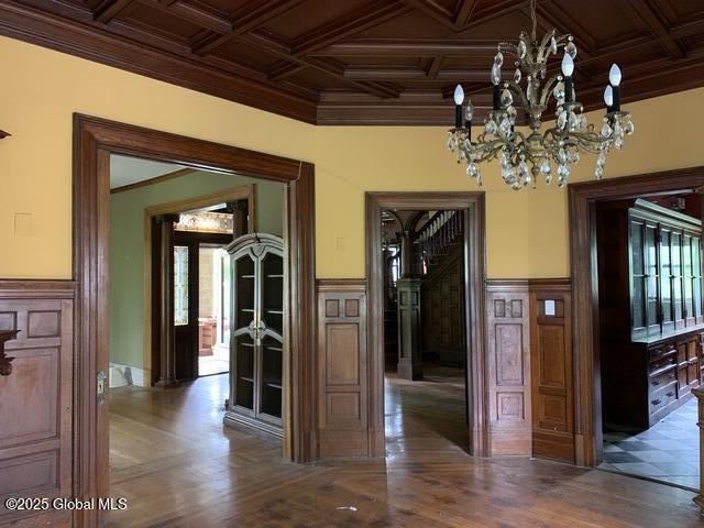1077 University Pl, Schenectady, NY 12308 - unfurnished dining area featuring a chandelier, coffered ceiling, ornamental molding, a wainscoted wall, and wood finished floors