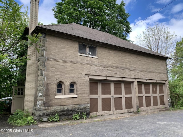 1077 University Pl, Schenectady, NY 12308 - view of home's exterior featuring brick siding, a garage, a chimney, asphalt driveway, and a shingled roof