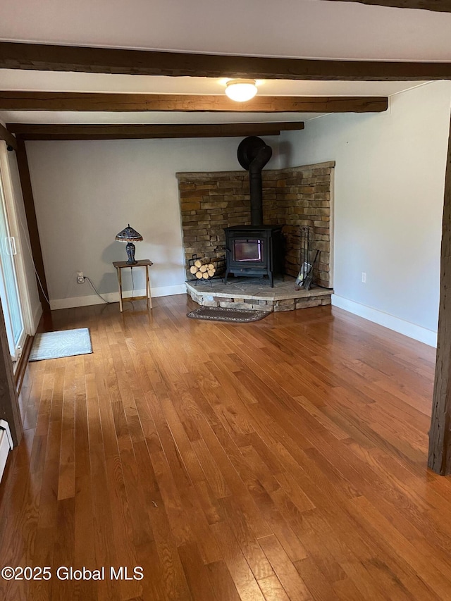 162 Garnet Lake Rd, Thurman, NY 12885 - unfurnished living room featuring beam ceiling, wood finished floors, a wood stove, and baseboards