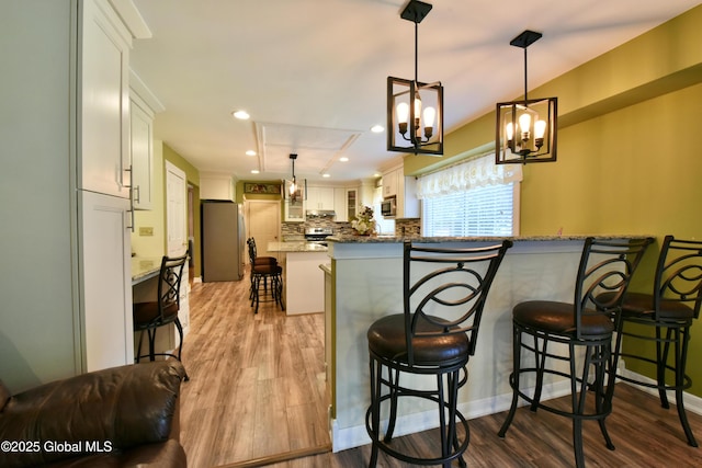 110 Old Coach Rd, Clifton Park, NY 12065 - kitchen with stainless steel appliances, a kitchen bar, decorative backsplash, wood finished floors, and recessed lighting