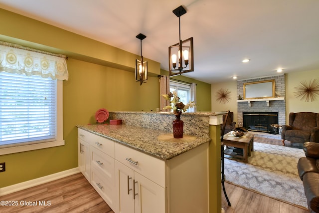 110 Old Coach Rd, Clifton Park, NY 12065 - kitchen featuring a peninsula, a brick fireplace, white cabinetry, open floor plan, and light stone counters