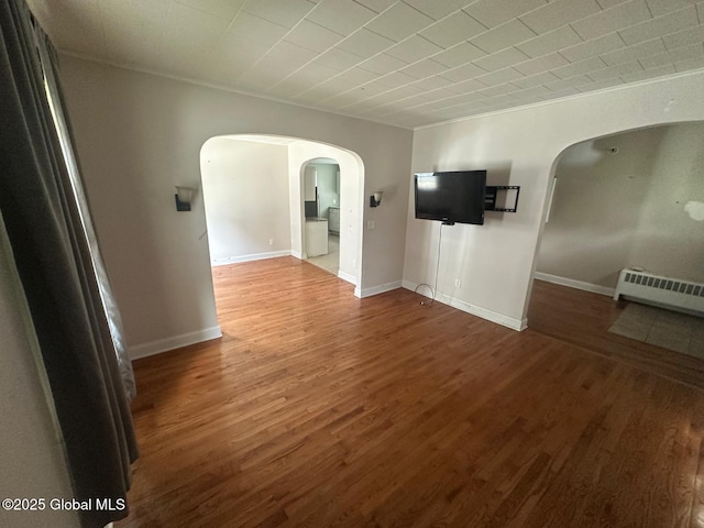 4 Ball Pl, Watervliet, NY 12189 - unfurnished living room featuring arched walkways, a baseboard heating unit, wood finished floors, and baseboards