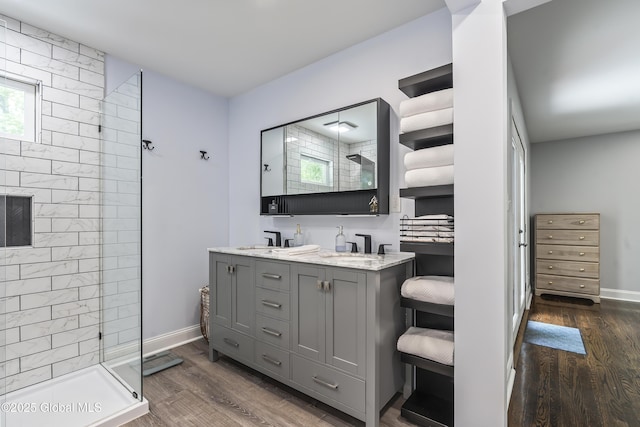 91 Gorman Rd, Menands, NY 12204 - bathroom featuring a tile shower, double vanity, wood finished floors, and baseboards