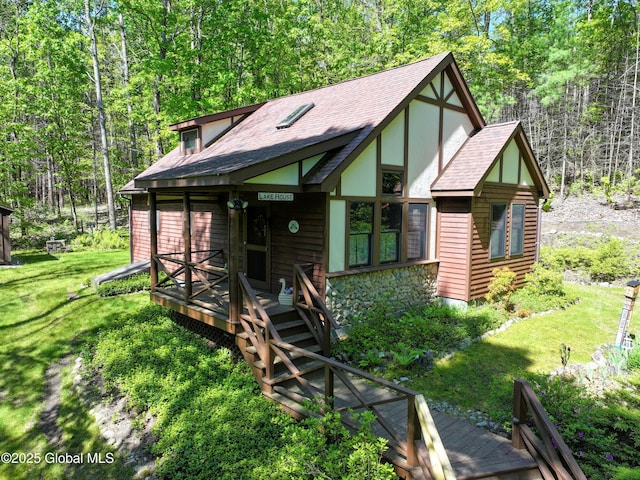 268 Dodd Hill Rd, Hague, NY 12836 - view of front of house with a shingled roof, a front lawn, a deck, a wooded view, and stone siding