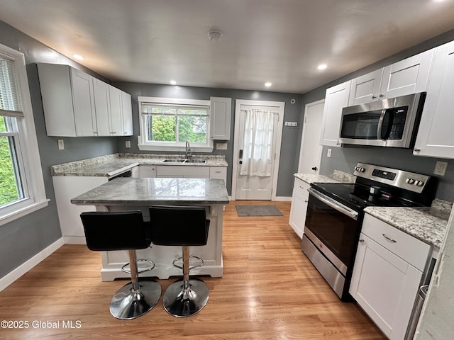 134 Moyer St, Canajoharie, NY 13317 - kitchen with stainless steel appliances, a sink, a breakfast bar area, light stone counters, and baseboards