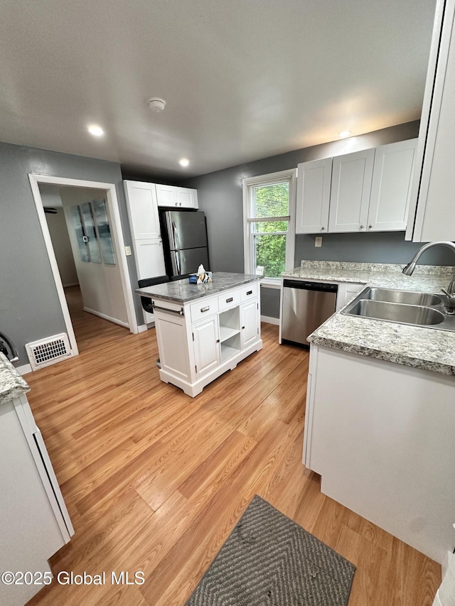 134 Moyer St, Canajoharie, NY 13317 - kitchen with stainless steel appliances, a sink, light wood-style flooring, white cabinetry, and a center island