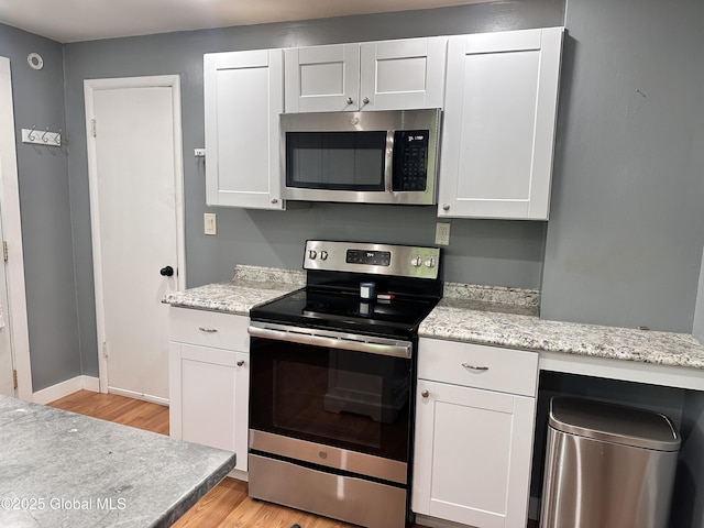 134 Moyer St, Canajoharie, NY 13317 - kitchen featuring stainless steel appliances, light wood-type flooring, white cabinets, light stone countertops, and baseboards