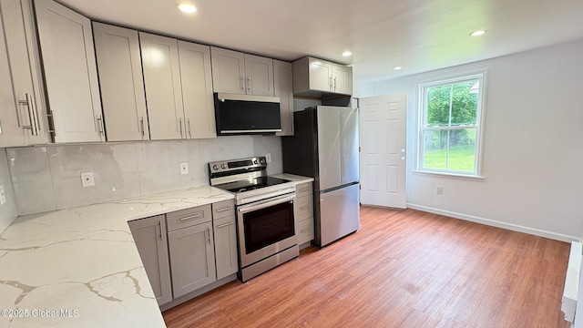 27 Major Dickinson Ave, Stillwater, NY 12170 - kitchen featuring stainless steel appliances, gray cabinetry, light wood-style floors, decorative backsplash, and light stone counters