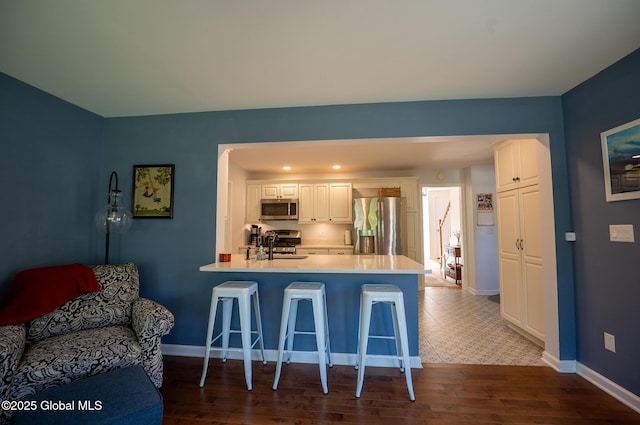 95 Jordan Blvd, Bethlehem, NY 12054 - kitchen featuring stainless steel appliances, a kitchen breakfast bar, a peninsula, white cabinetry, and light countertops