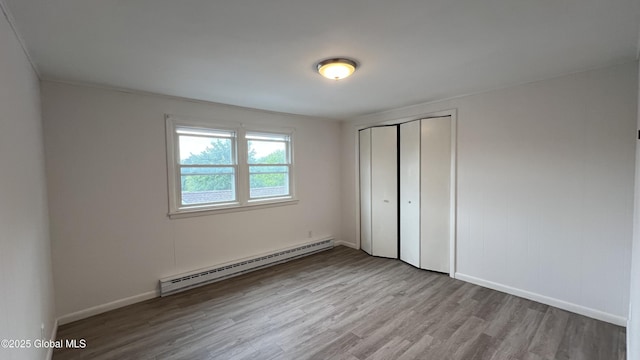 209 Hudson Ave E, East Greenbush, NY 12144 - unfurnished bedroom with a baseboard heating unit, wood finished floors, a closet, and baseboards