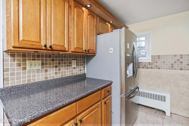 5 Brigadier St, Colonie, NY 12205 - kitchen with radiator heating unit, stainless steel refrigerator with ice dispenser, light tile patterned floors, tile walls, and dark stone countertops