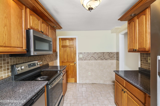5 Brigadier St, Colonie, NY 12205 - kitchen with stainless steel appliances, light tile patterned floors, dark stone counters, brown cabinets, and tile walls
