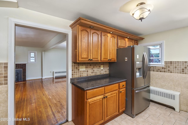 5 Brigadier St, Colonie, NY 12205 - kitchen featuring radiator heating unit, stainless steel refrigerator with ice dispenser, tile walls, brown cabinets, and dark stone countertops