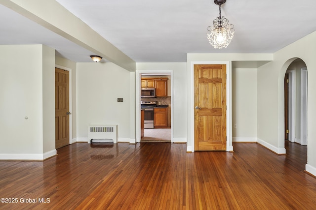 5 Brigadier St, Colonie, NY 12205 - unfurnished room with radiator heating unit, arched walkways, dark wood finished floors, a chandelier, and baseboards