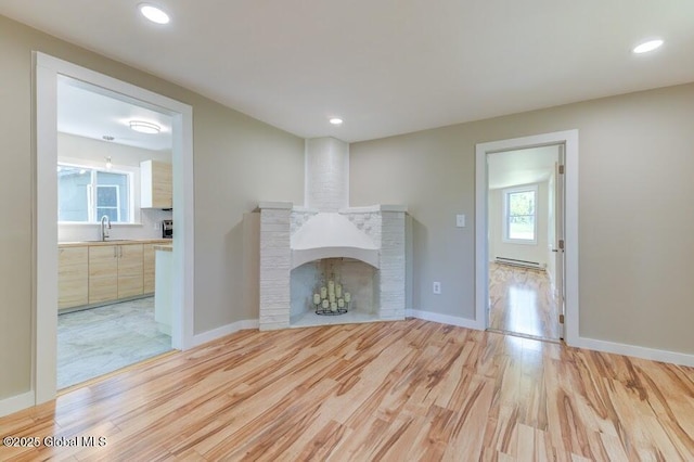 3956 Rte 9 W, Saugerties, NY 12477 - unfurnished living room featuring a brick fireplace, a baseboard heating unit, a sink, light wood-style flooring, and recessed lighting