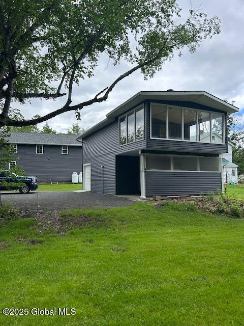 3916 State Highway 2, Brunswick, NY 12180 - back of house with a sunroom, an attached garage, a lawn, and driveway