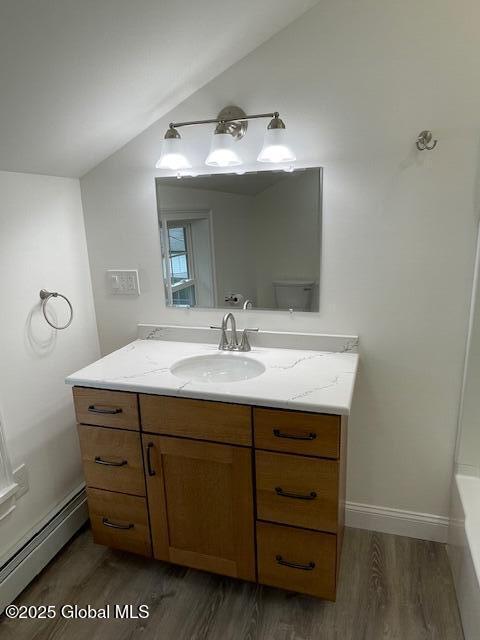 3916 State Highway 2, Brunswick, NY 12180 - full bath featuring baseboard heating, wood finished floors, vanity, vaulted ceiling, and a tub