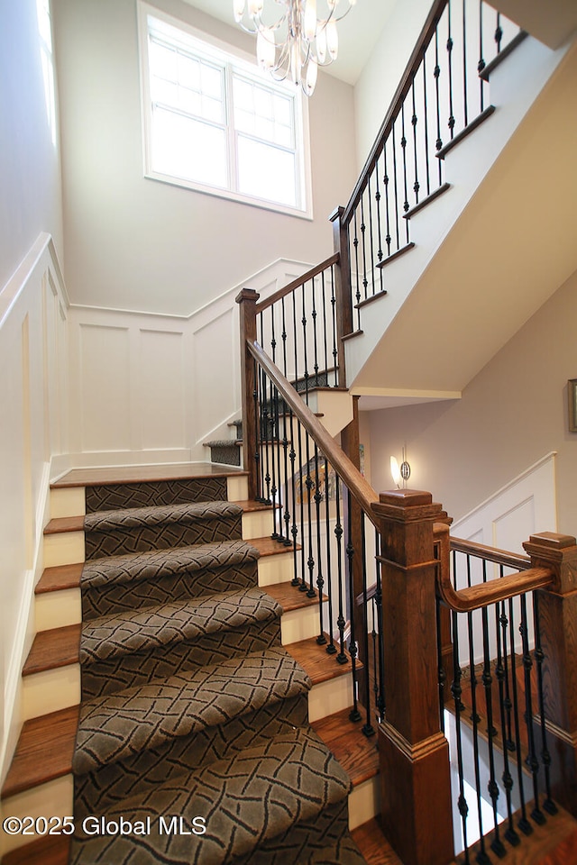 18 Rose Ter, Wilton, NY 12866 - stairway featuring a decorative wall, wood finished floors, a chandelier, and a wainscoted wall