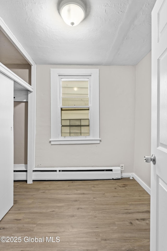 819 1st St, Rensselaer, NY 12144 - unfurnished room with wood finished floors, baseboards, baseboard heating, and a textured ceiling