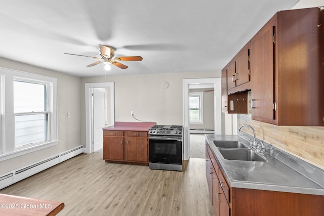 819 1st St, Rensselaer, NY 12144 - kitchen with gas stove, a sink, a baseboard heating unit, brown cabinets, and light wood-style floors