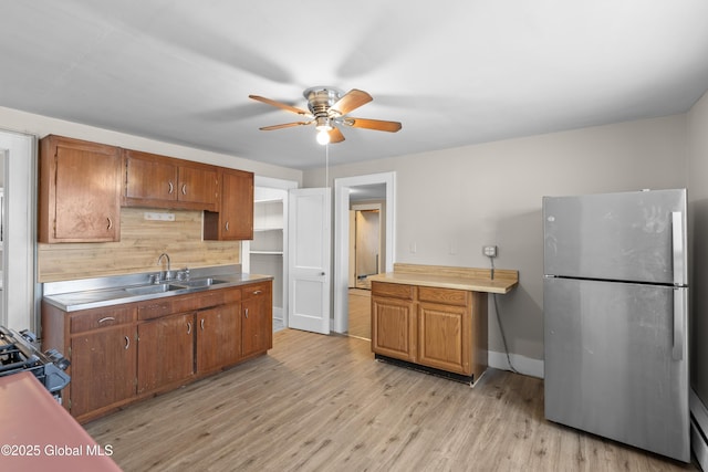 819 1st St, Rensselaer, NY 12144 - kitchen with freestanding refrigerator, a ceiling fan, light wood finished floors, brown cabinets, and a sink
