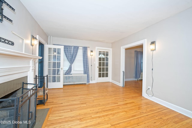 1013 Washington Ave, Albany, NY 12206 - unfurnished living room featuring radiator, light wood-style flooring, baseboards, and a fireplace with flush hearth